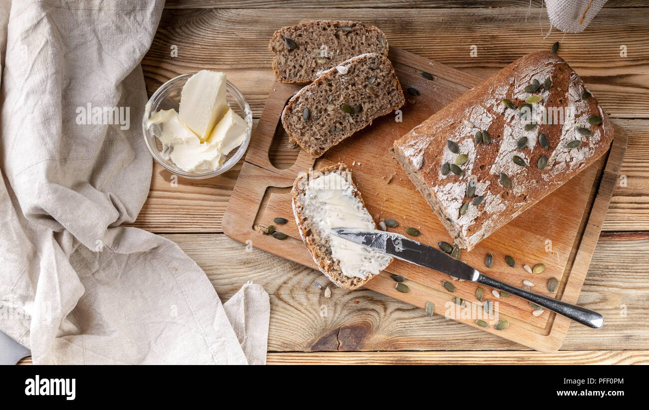 Homemade rye bread with pumpkin seeds and butter. Breakfast concept. Top view Stock Photo