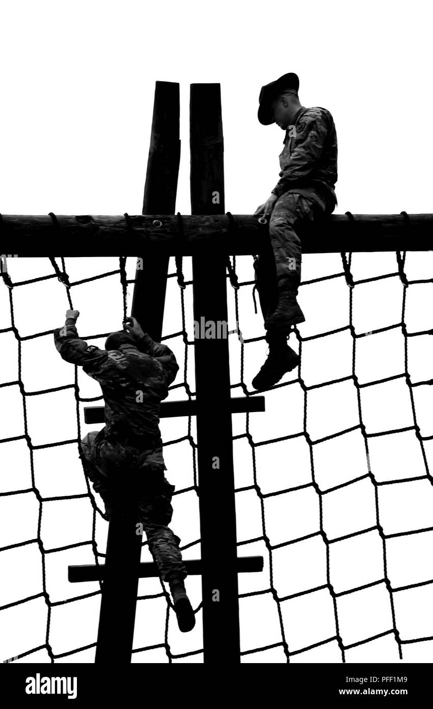 A 98th Training Division (Initial Entry Training) drill sergeant watches Sgt. Camille Edward, a healthcare specialist with 352nd Combat Support Hospital, 807th Medical Command (Deployment Support), manuever an obstacle at the 2018 U.S. Army Reserve Command's Best Warrior Competition in Fort Bragg, North Carolina June 10-15.  More than 35 Soldiers representing seven Geographic Commands and 22 Functional Commands, will spend the week competing in a variety of challenges including firing weapons, land navigation, the Army Physical Fitness Test, and various mystery events. These challenges will ul Stock Photo