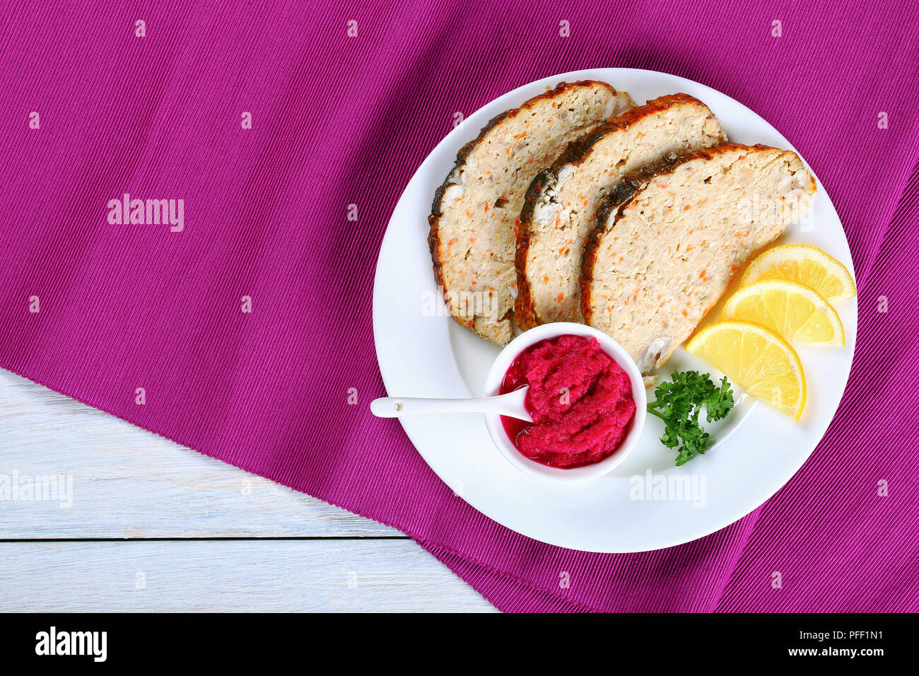 Jewish carp or minced-fish forcemeat stuffed inside the fish skin, cut in slices and served  with lemon slices and horseradish flavored with beetroot, Stock Photo