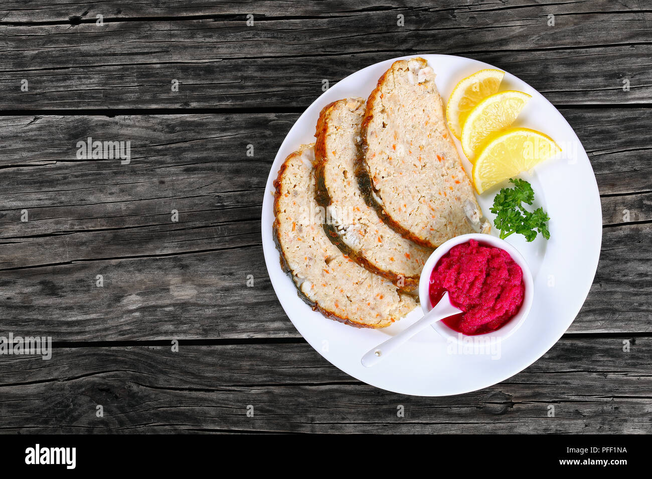 Jewish whitefish or minced-fish forcemeat stuffed inside the fish skin, cut in slices and served  with lemon slices and horseradish flavored with beet Stock Photo