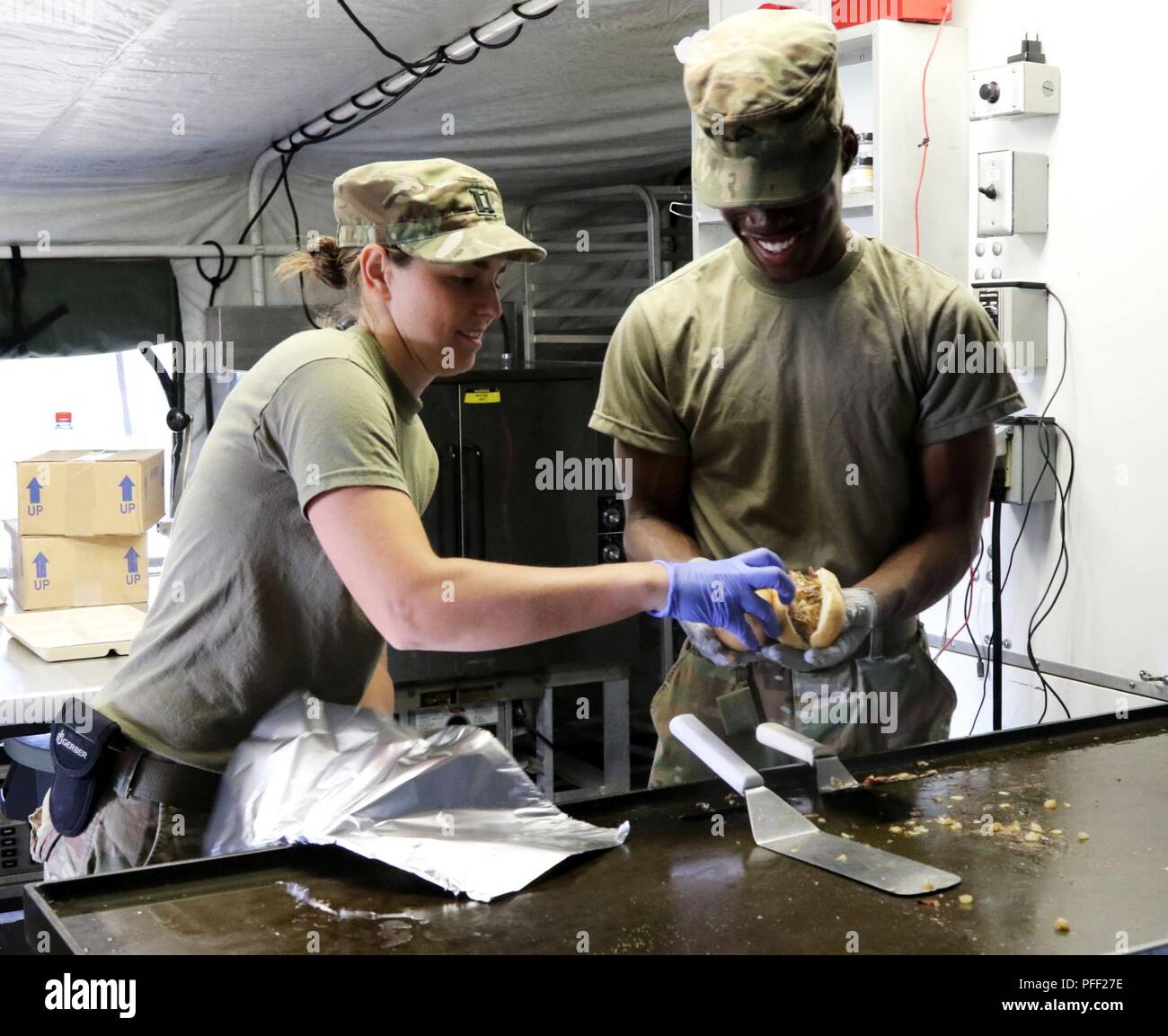 Capt. Abby Steiner, the officer in charge of the nutrition division of the 212th Combat Support Hospital, based in the Rhine Ordnance Barracks, Kaiserslautern, Germany, and Pfc. Shane Rose, a nutrition care specialist, package a sandwich they made for the soldiers of the CSH on June 11, 2018. Steiner, originally from Pioneer, Ohio, and Rose, a native of Constitution Hill, Jamaica, are in Swidwin, Poland, participating in Saber Strike 18 a multi-national exercise that is designed to practice the interoperability of the many countries who are participating. (Michigan National Guard Stock Photo