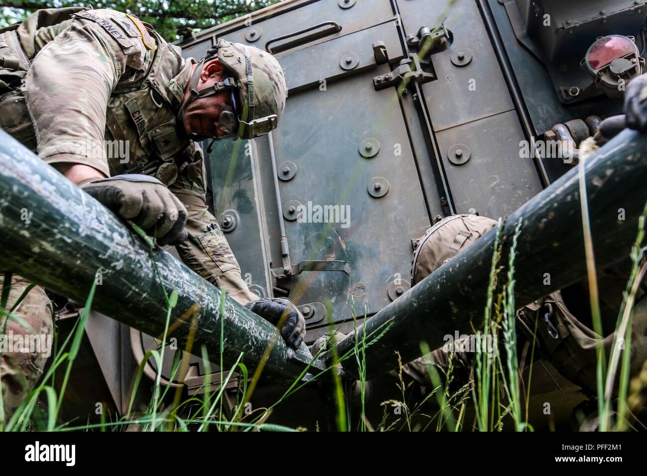 Sgt. Eric Cherney, vehicle commander with 1st Squadron, 2nd Cavalry Regiment, maintains an Interim Armored Vehicle 'Stryker” with another Soldier during exercise Puma 2 with Battle Group Poland at Bemowo Piskie Training Area, Poland on June 13, 2018 in the midst of Saber Strike 18. This year's exercise, which runs from June 3-15, tests allies and partners from 19 countries on their ability work together to deter aggression in the region and improve each unit's ability to perform their designated mission. Stock Photo