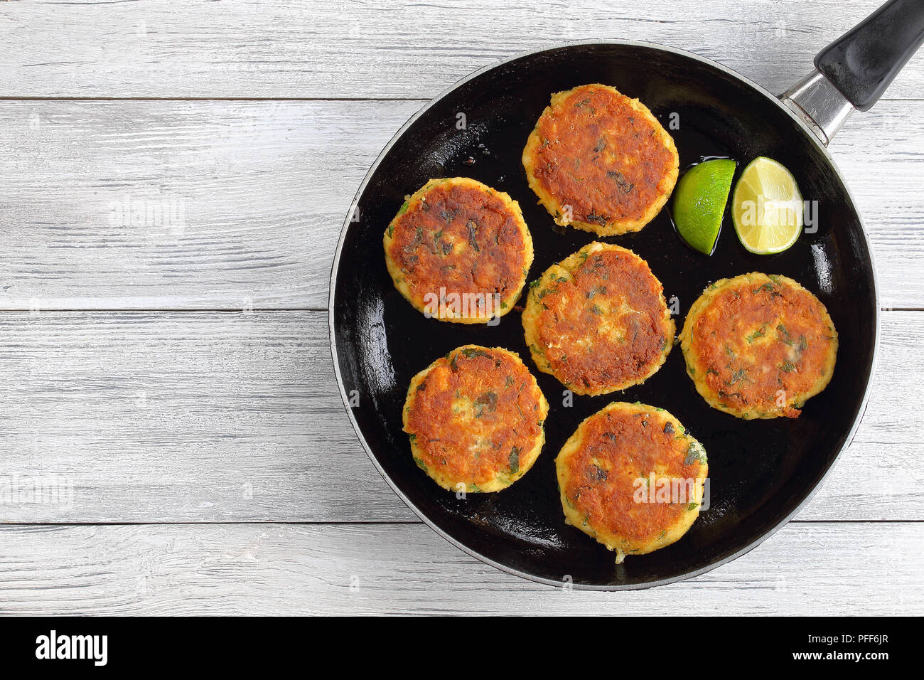 delicious fresh fried fish cakes on skillet with lime slices, authentic