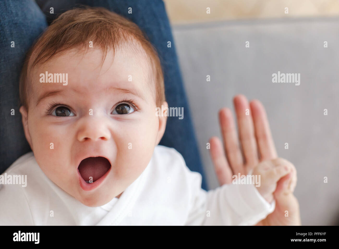 Surprised baby holding mother hand Stock Photo