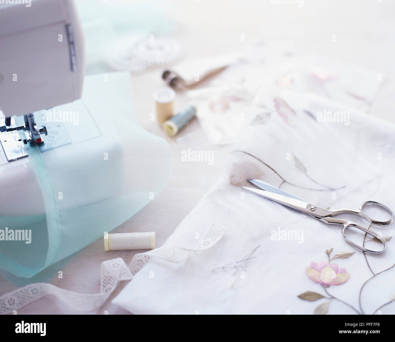 Sewing machine, cotton reels, material and scissors scattered on a table Stock Photo Alamy