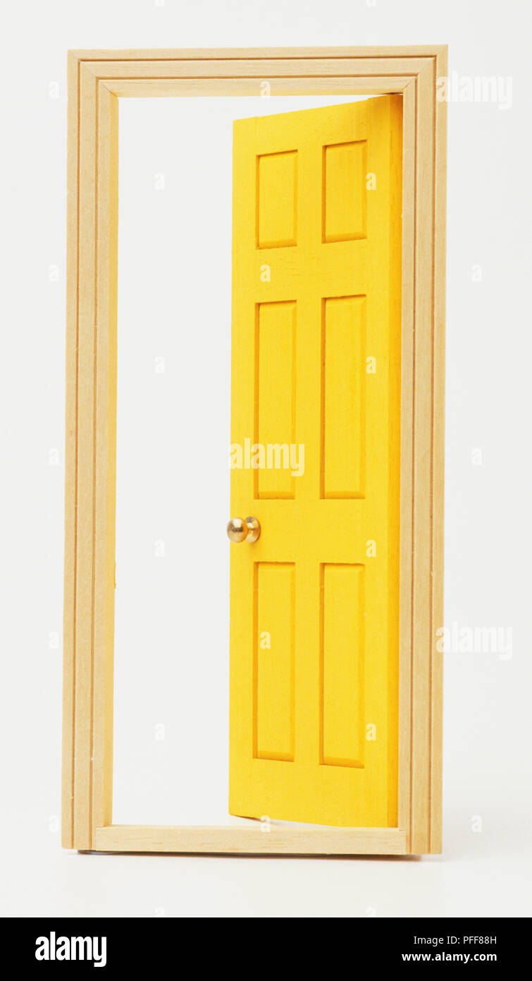 Yellow door ajar in wooden door frame, front view. Stock Photo