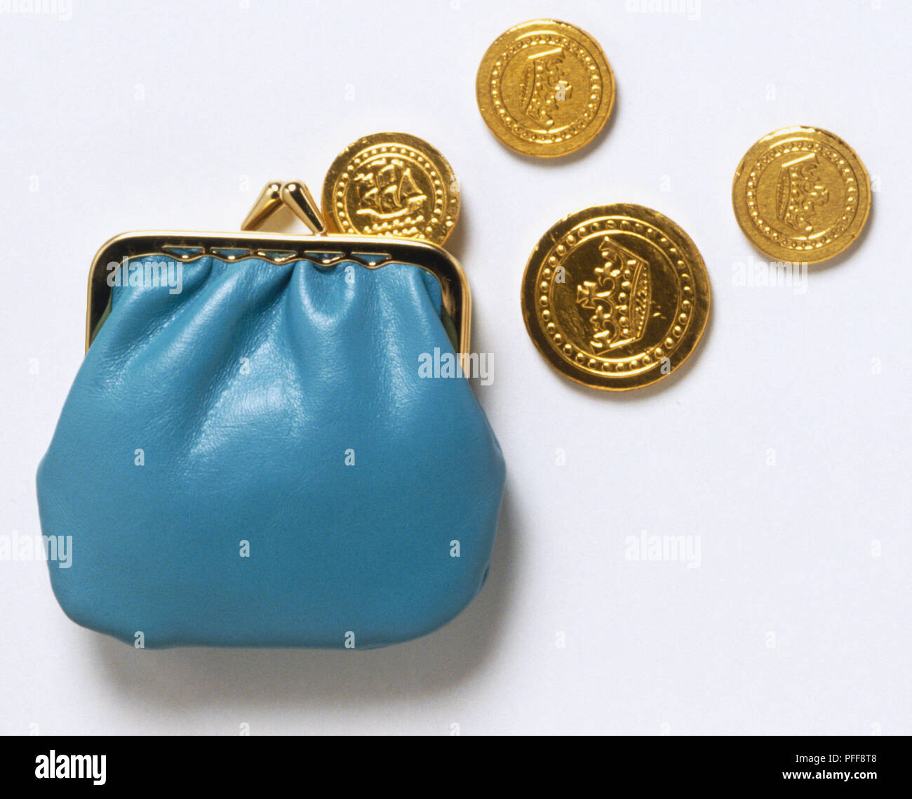 Blue clasp purse and scattered gold coin, close up. Stock Photo