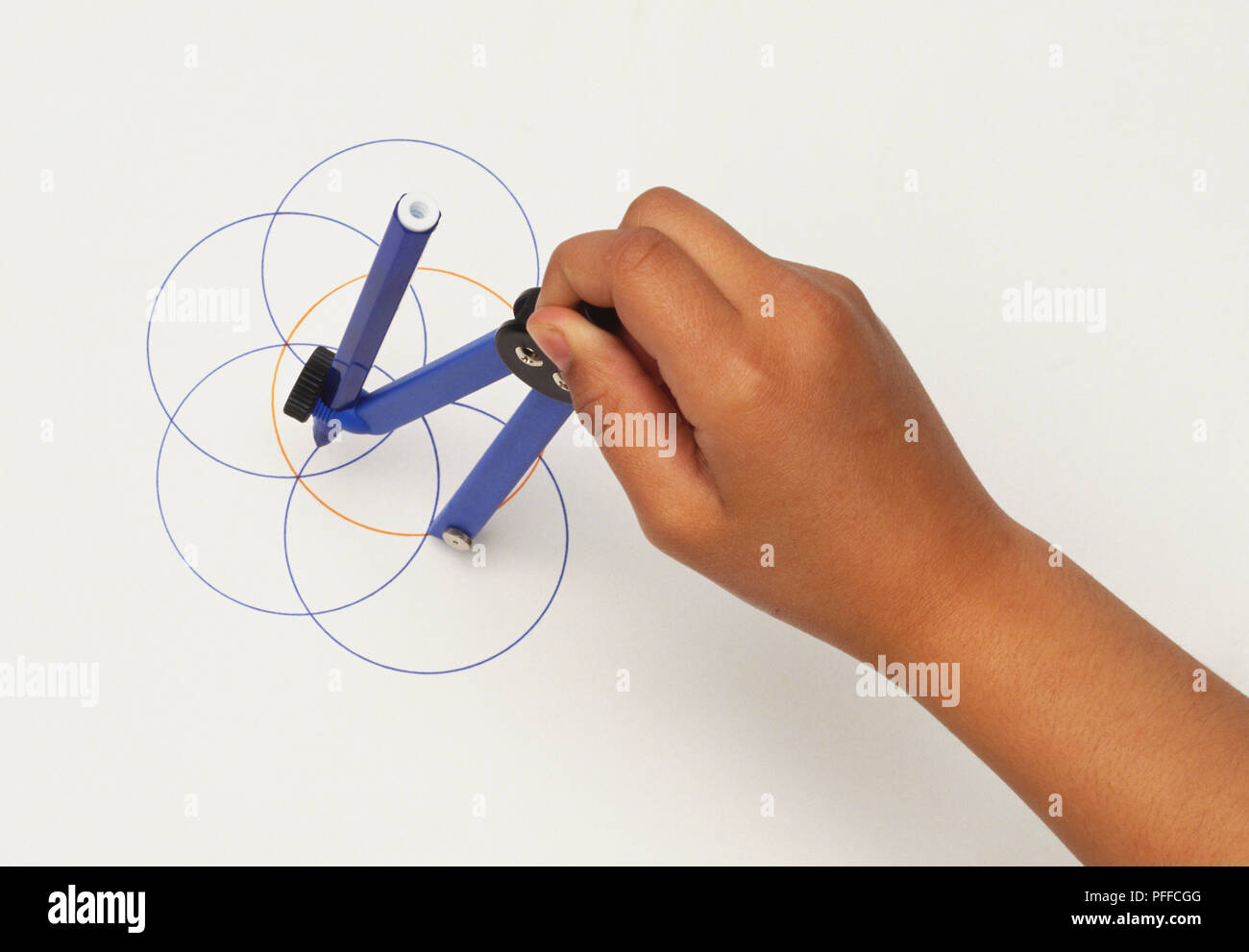 Hand holding mathematics compass, drawing circles, above shot Stock