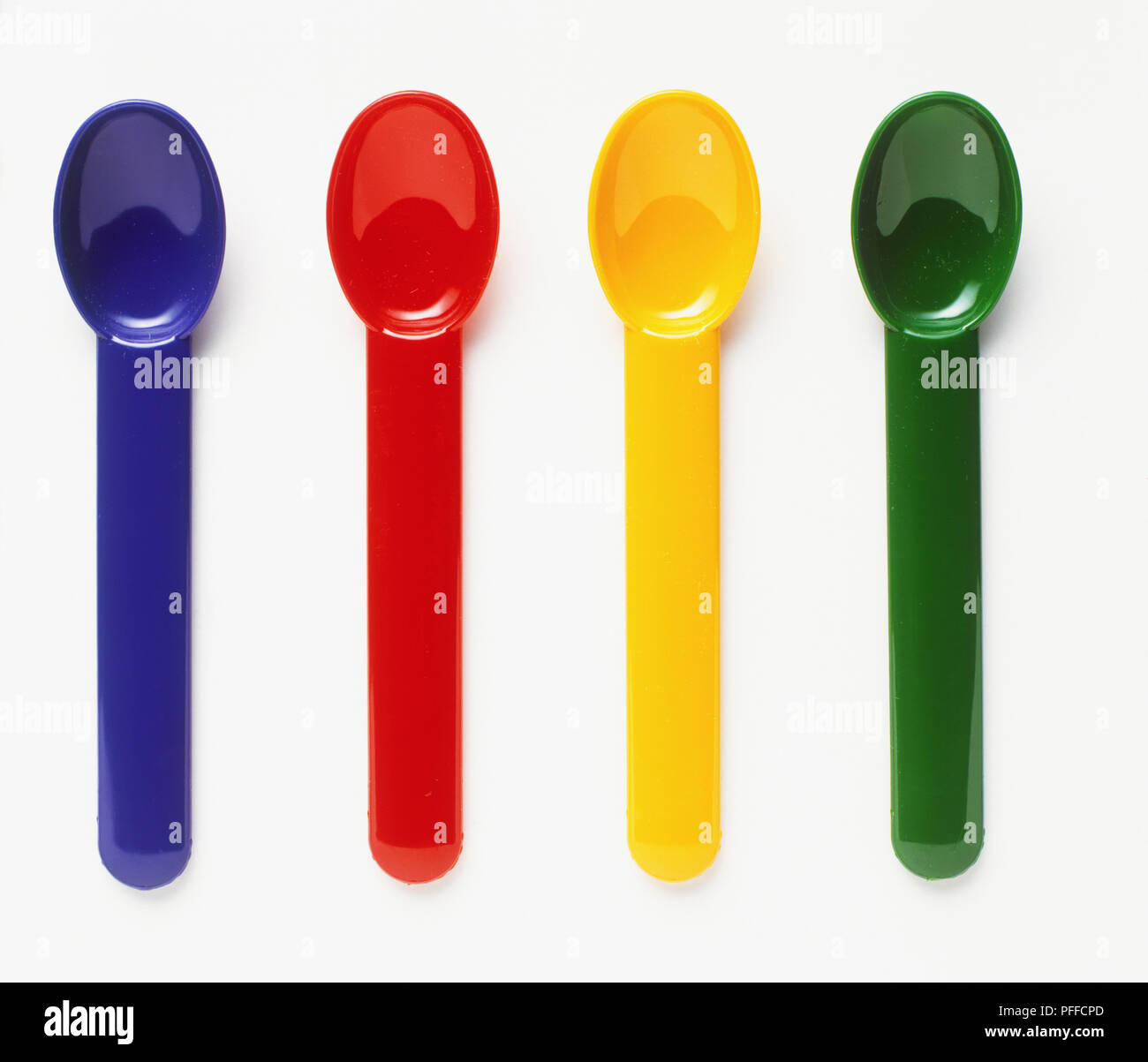 Different coloured plastic spoons, blue, red, yellow and green Stock