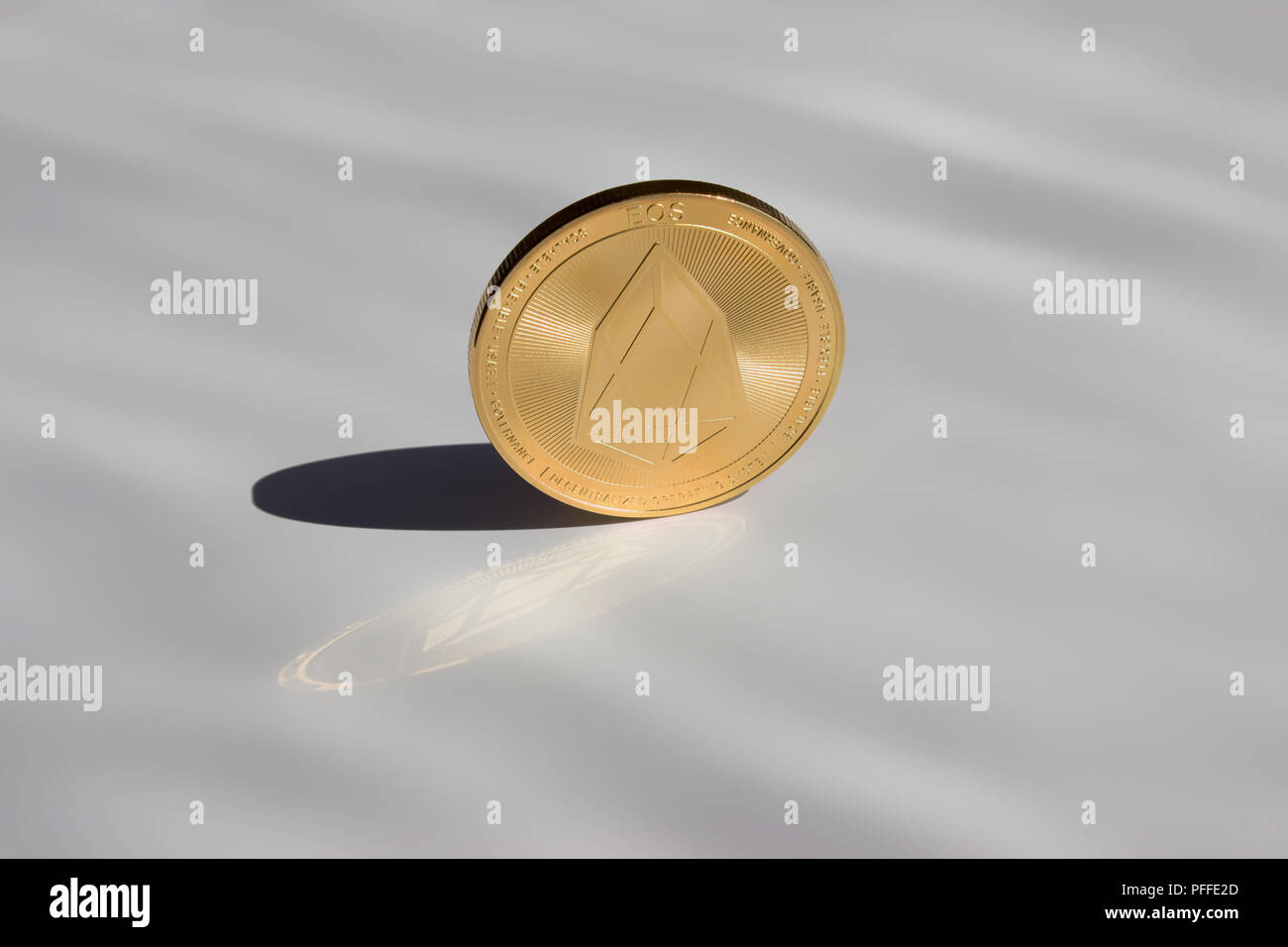 On a white gray background is coin of a digital crypto  currency - eos and their reflection and shadow. Stock Photo