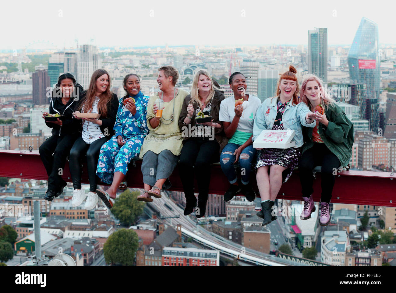 Winners of a competition enjoy a meal 450ft up on the roof of a central London skyscraper, as Deliveroo recreates 'Lunch Atop a Skyscraper', the photograph taken during the construction of the Rockefeller Center in New York City, 1932. Stock Photo