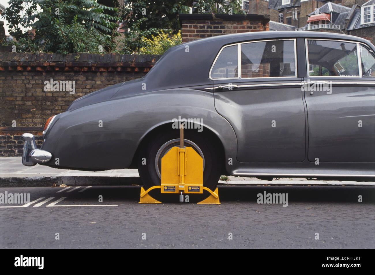 England, London, parked car with a yellow clamp on its back wheel, side view. Stock Photo
