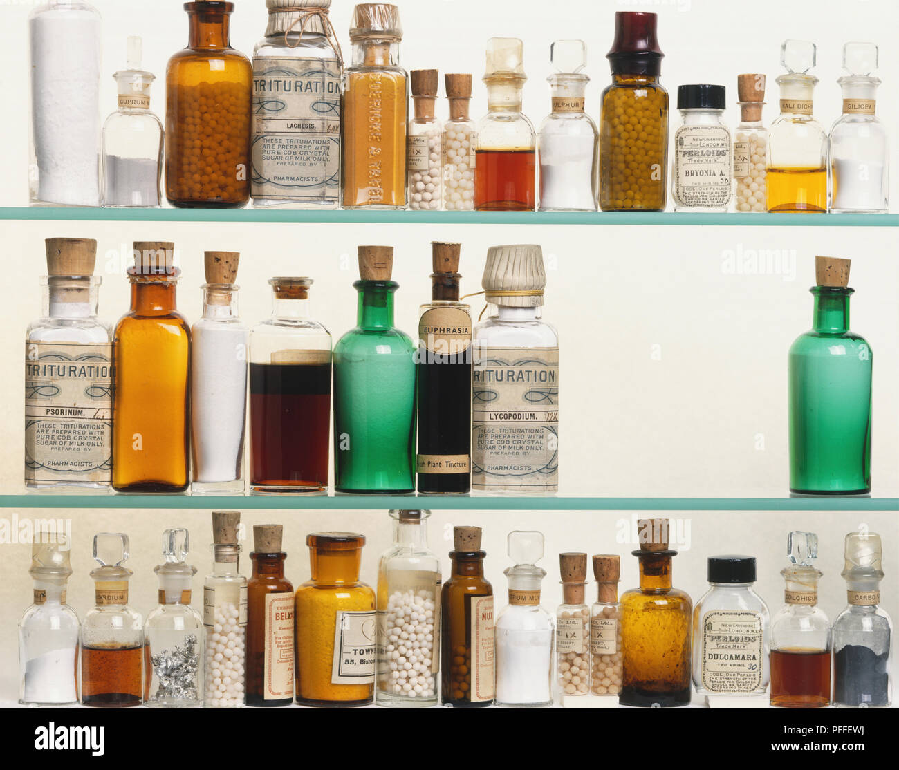 Selection of bottled homeopathic remedies displayed on shelves, front view. Stock Photo