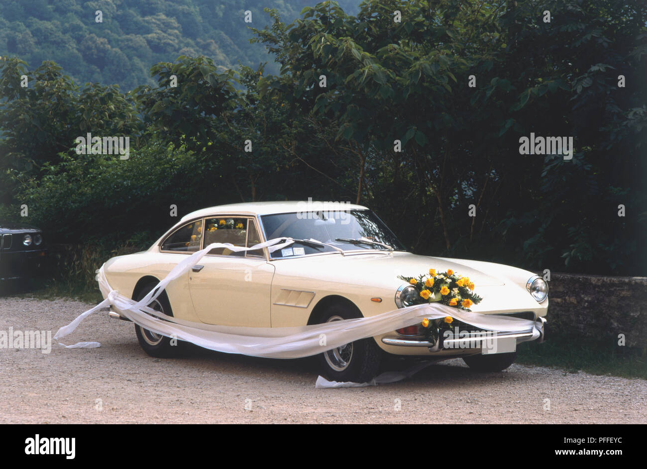 Vintage, cream-coloured Ferrari decorated for a wedding, with yellow flowers and white veil Stock Photo