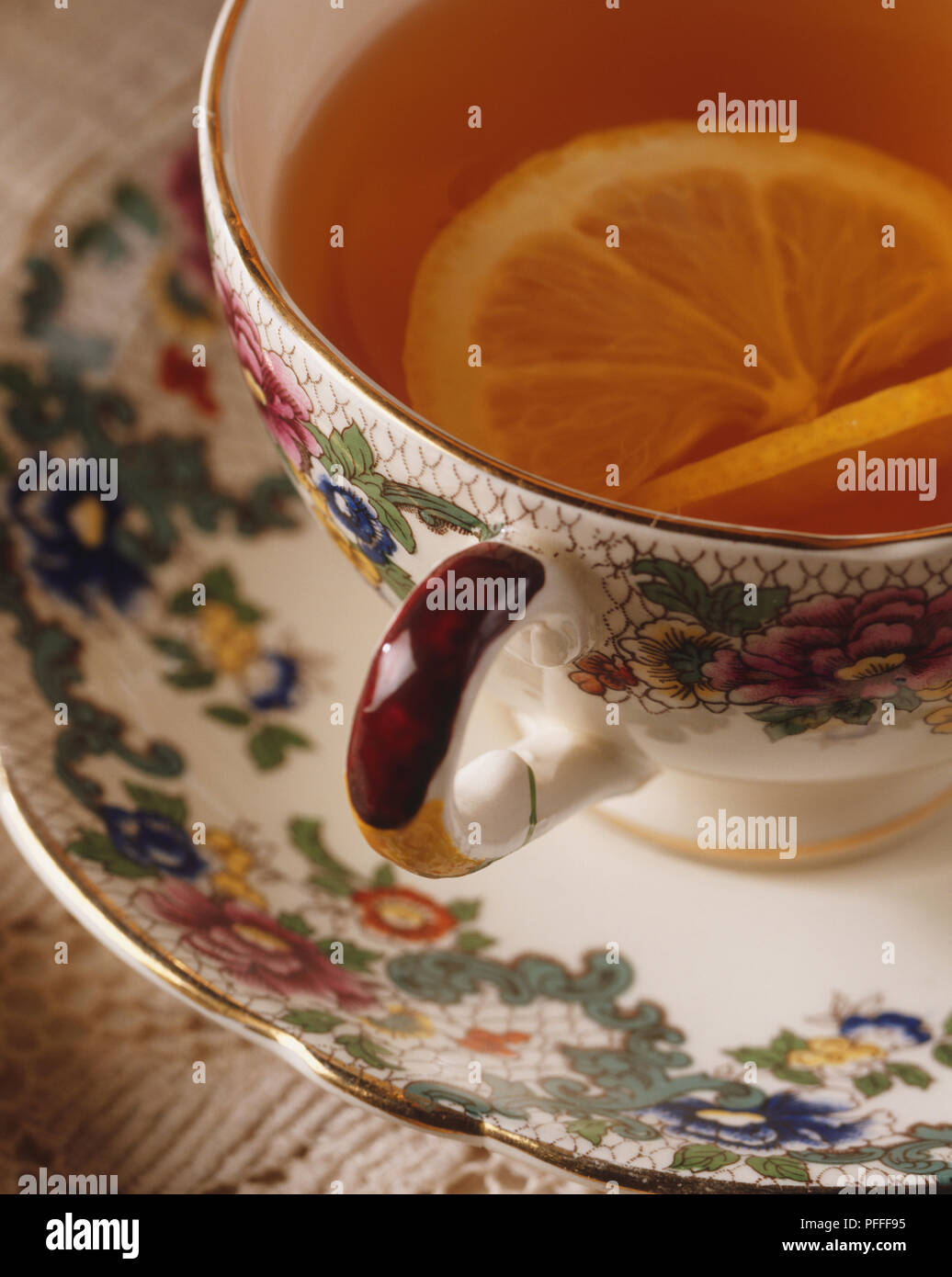 Tea served in a flower pattern china cup, garnished with a slice of lemon, close up, high angle view Stock Photo