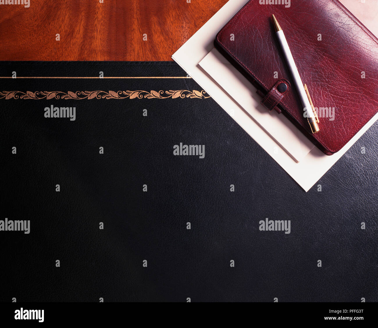 Wooden worksurface with a black leather insert and a personal organiser in the corner. Stock Photo