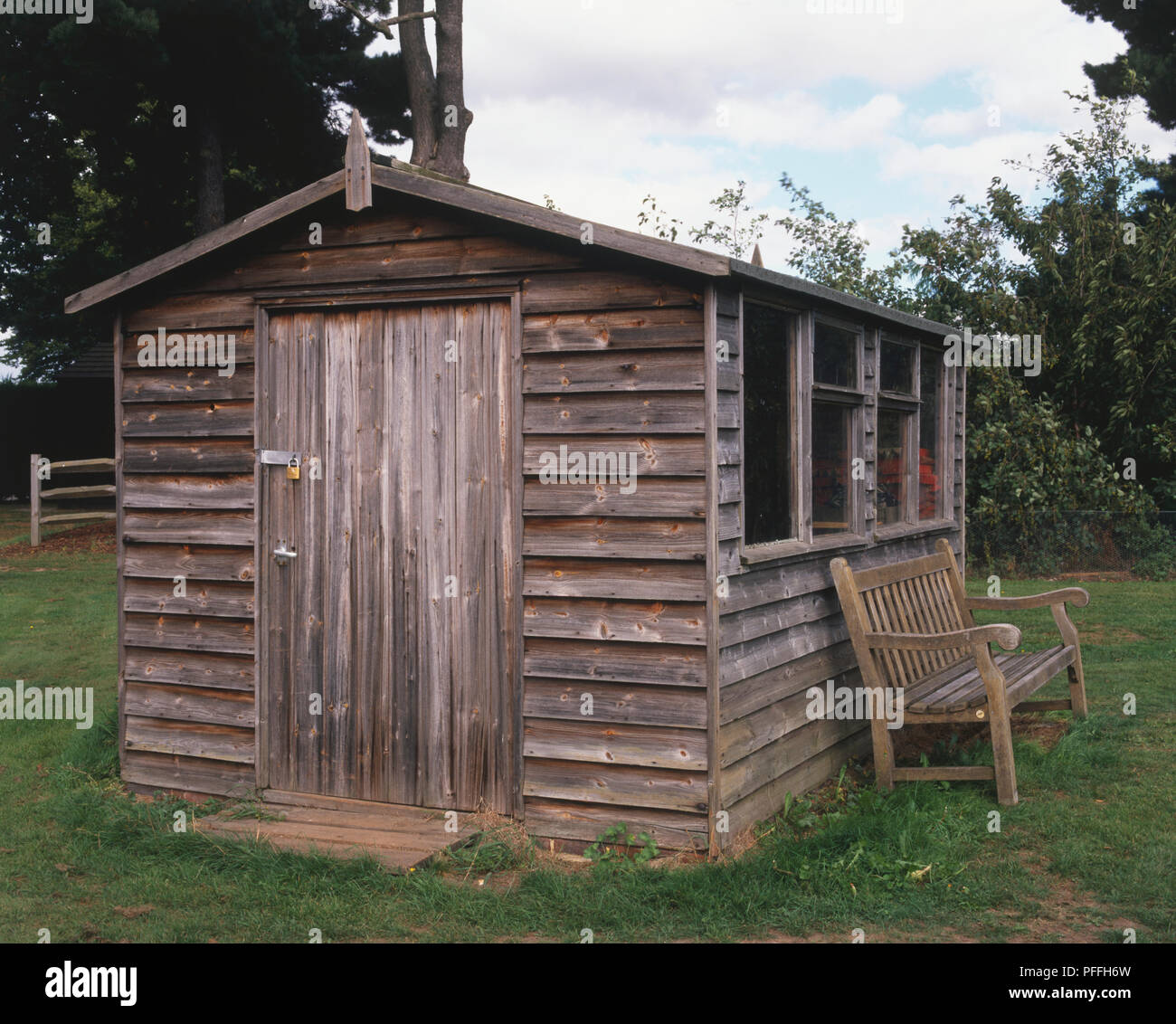 Garden Shed With Wooden Garden Bench Underneath Its Side Windows