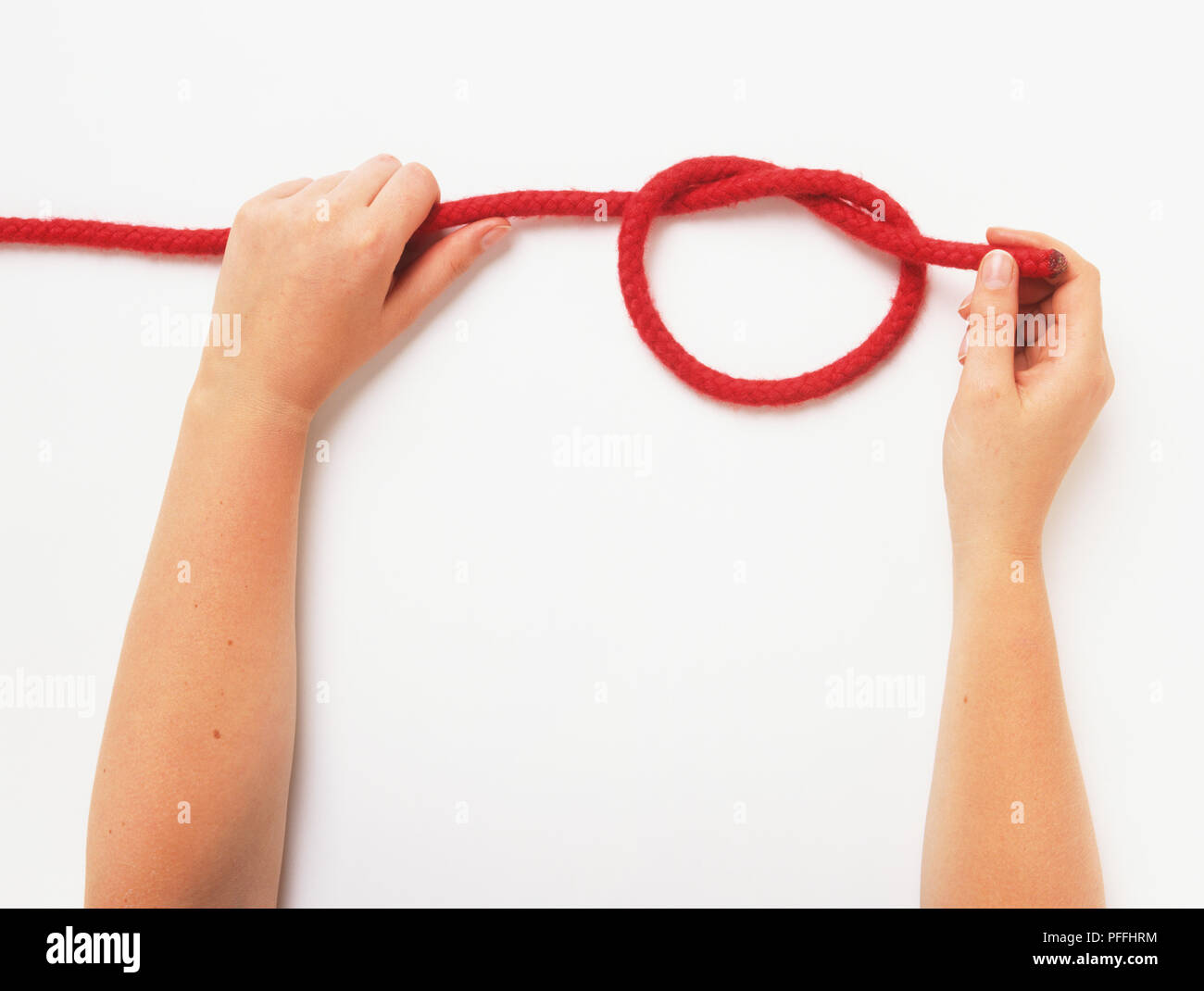 Hands pulling at both ends of a rope to secure a halfhitch knot Stock Photo Alamy
