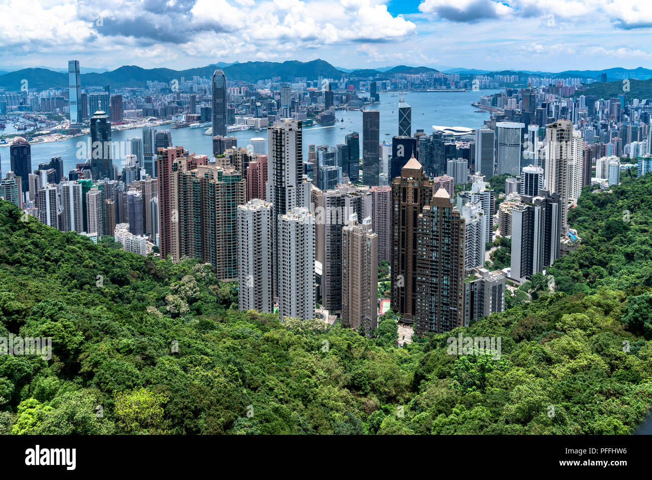 HongKong Skyline against a backdrop of green vegetation, blue ocean and distant mountains Stock Photo