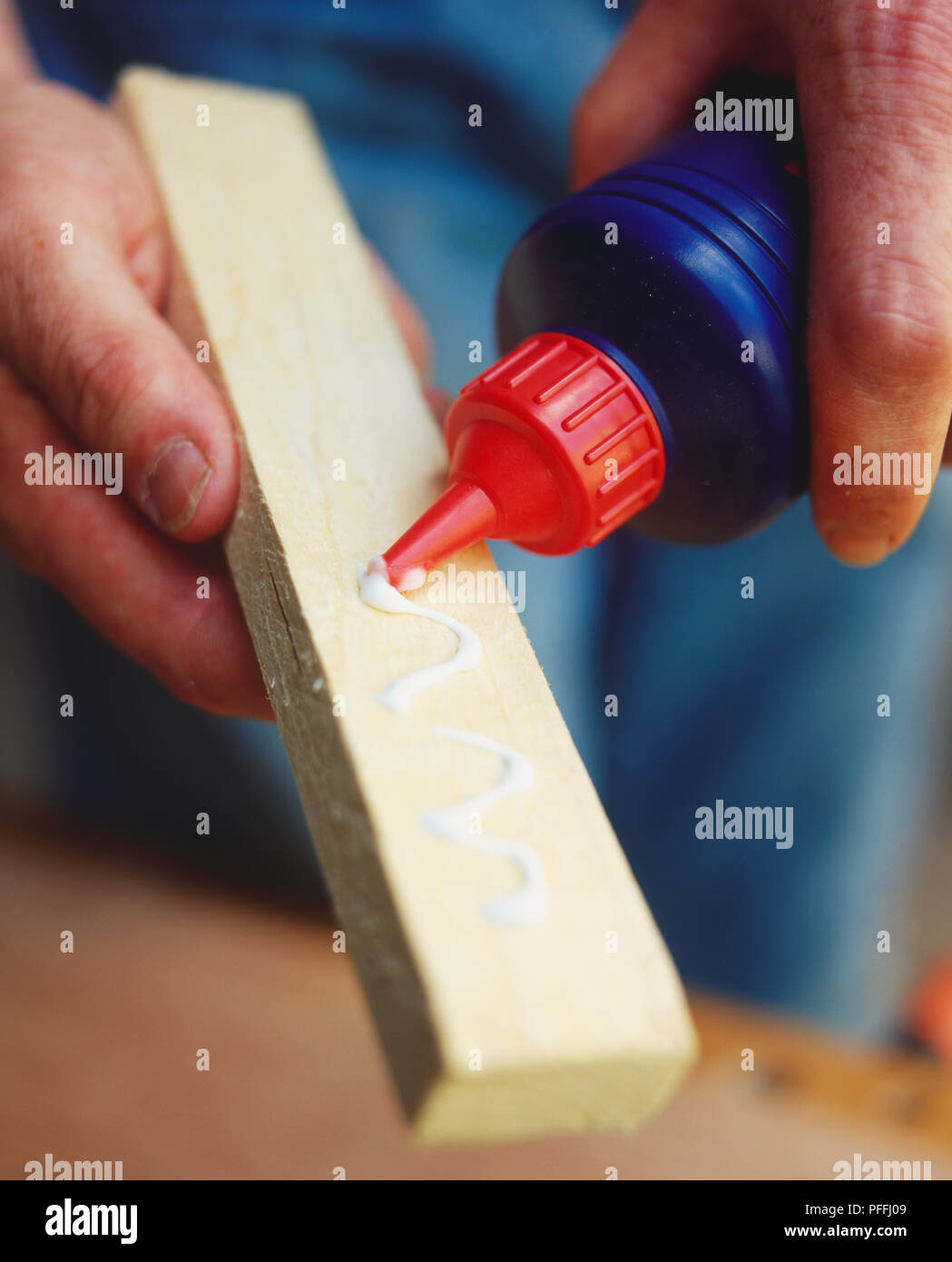Applying PVA glue to base of a piece of wood, close up. Stock Photo