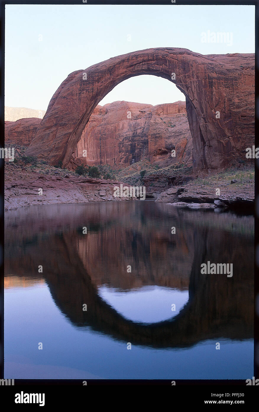 Rainbow Bridge National Monument, bathed in the setting sun on a spring evening, rising 88 m above Lake Powell and the largest natural arch in North America. Stock Photo