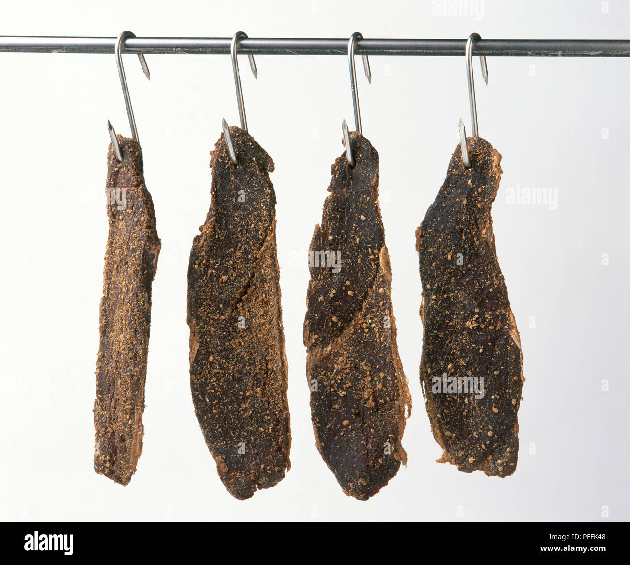 Cured biltong hanging from meat hooks Stock Photo