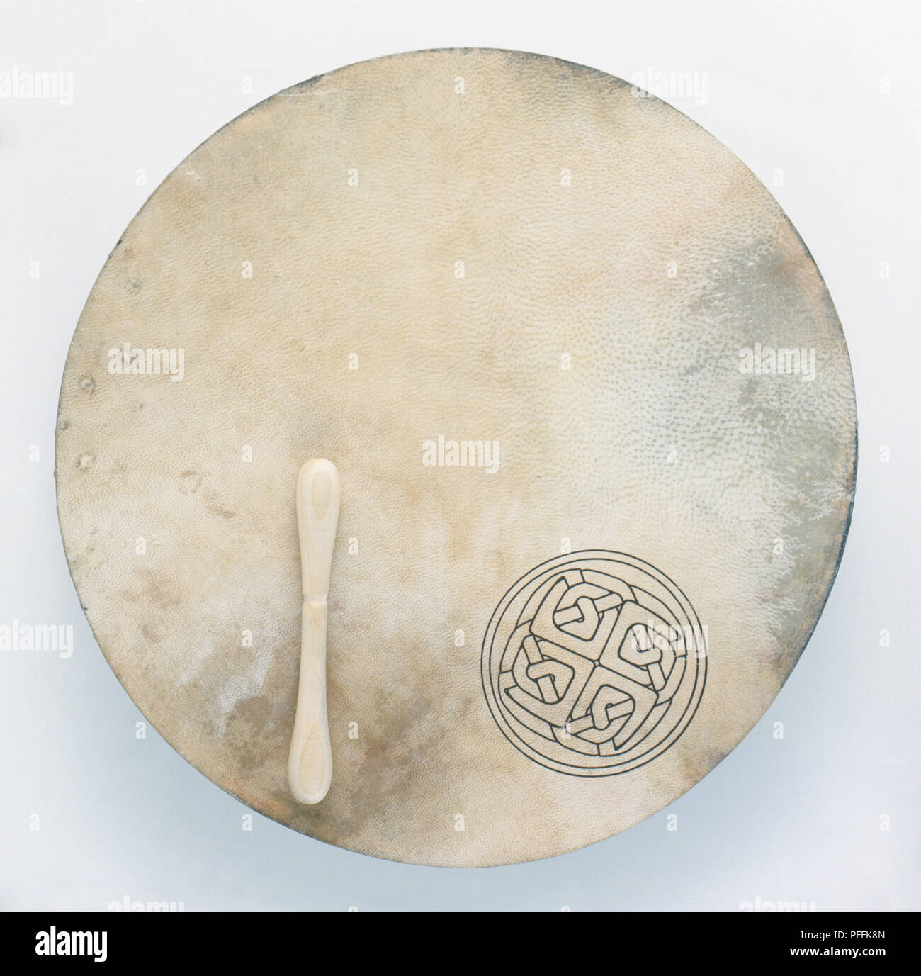 Traditional Irish handdrum with a Celtic symbol on it and a drum stick, closeup Stock Photo