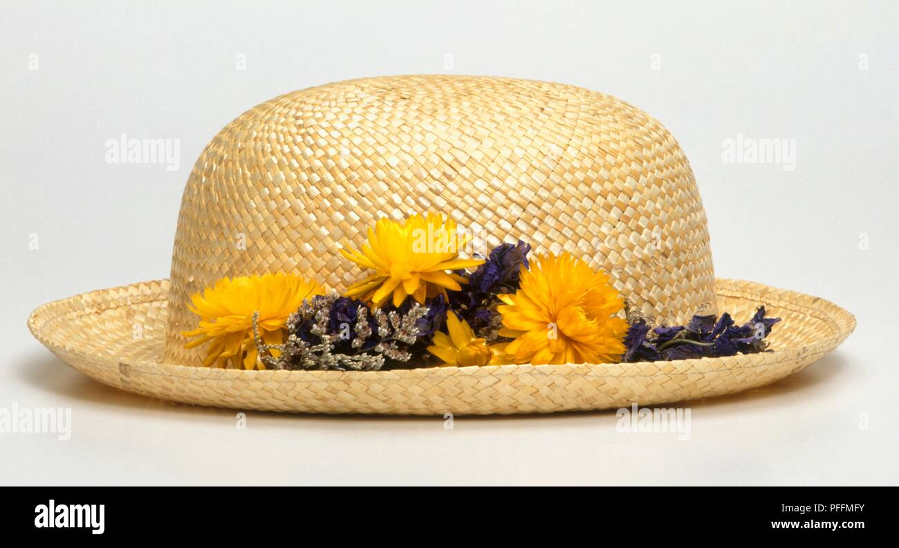 Straw hat with dried yellow flowers on the brim Stock Photo - Alamy