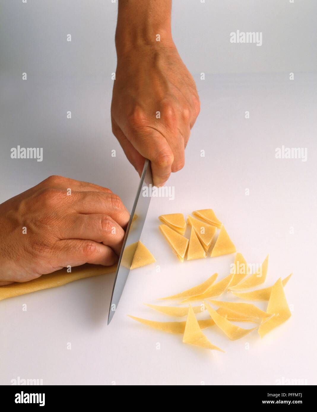 Using kitchen knife to cut maltagliati pasta dough into trapezoid
