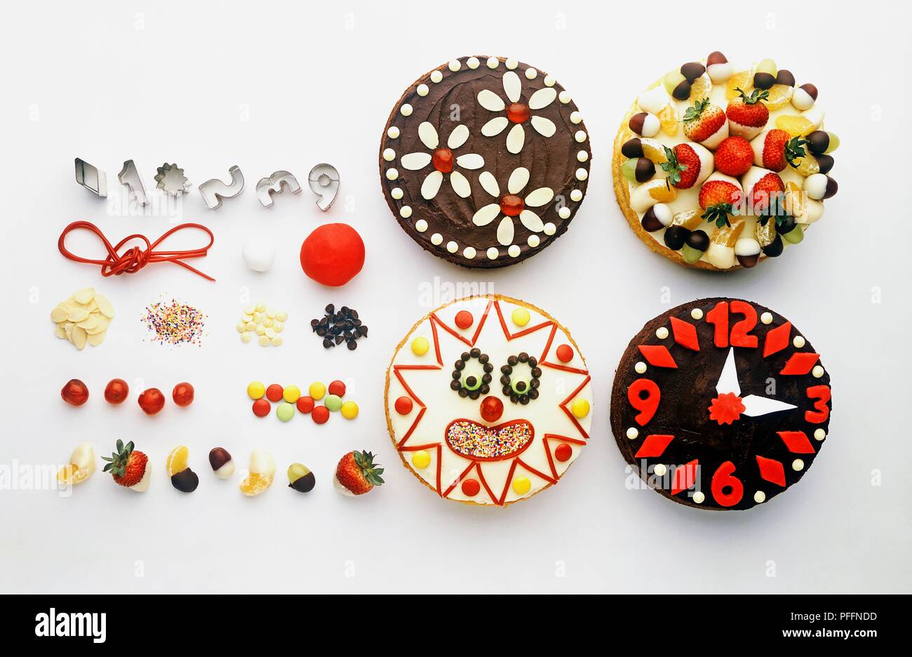 Four colourfully decorated cakes, with pastry cutters, ingredients, and