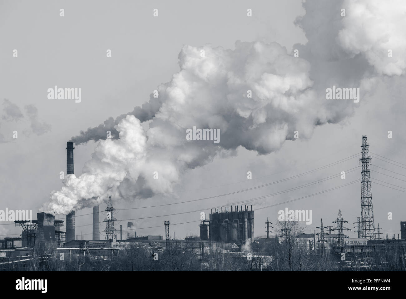 smoke stacks in a working factory emitting steam, smog and air pollution. Stock Photo