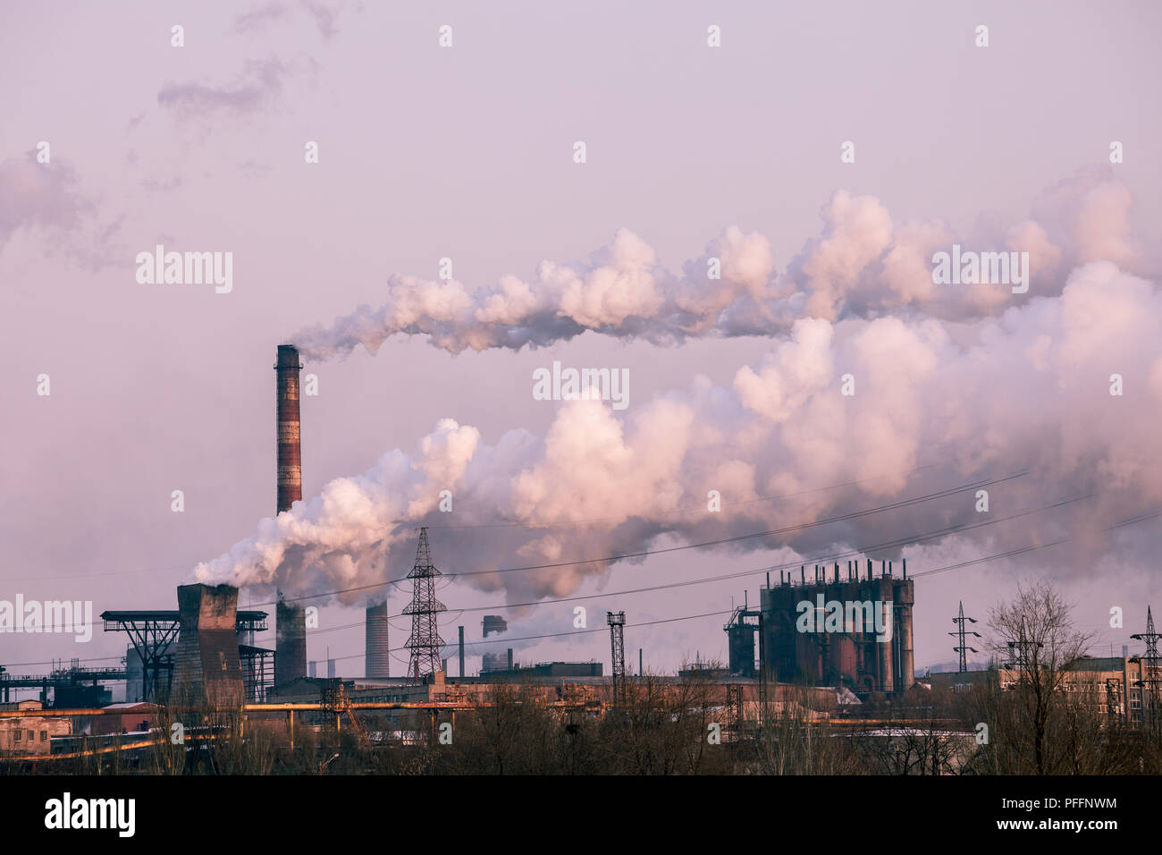 smoke stacks in a working factory emitting steam, smog and air pollution. Stock Photo