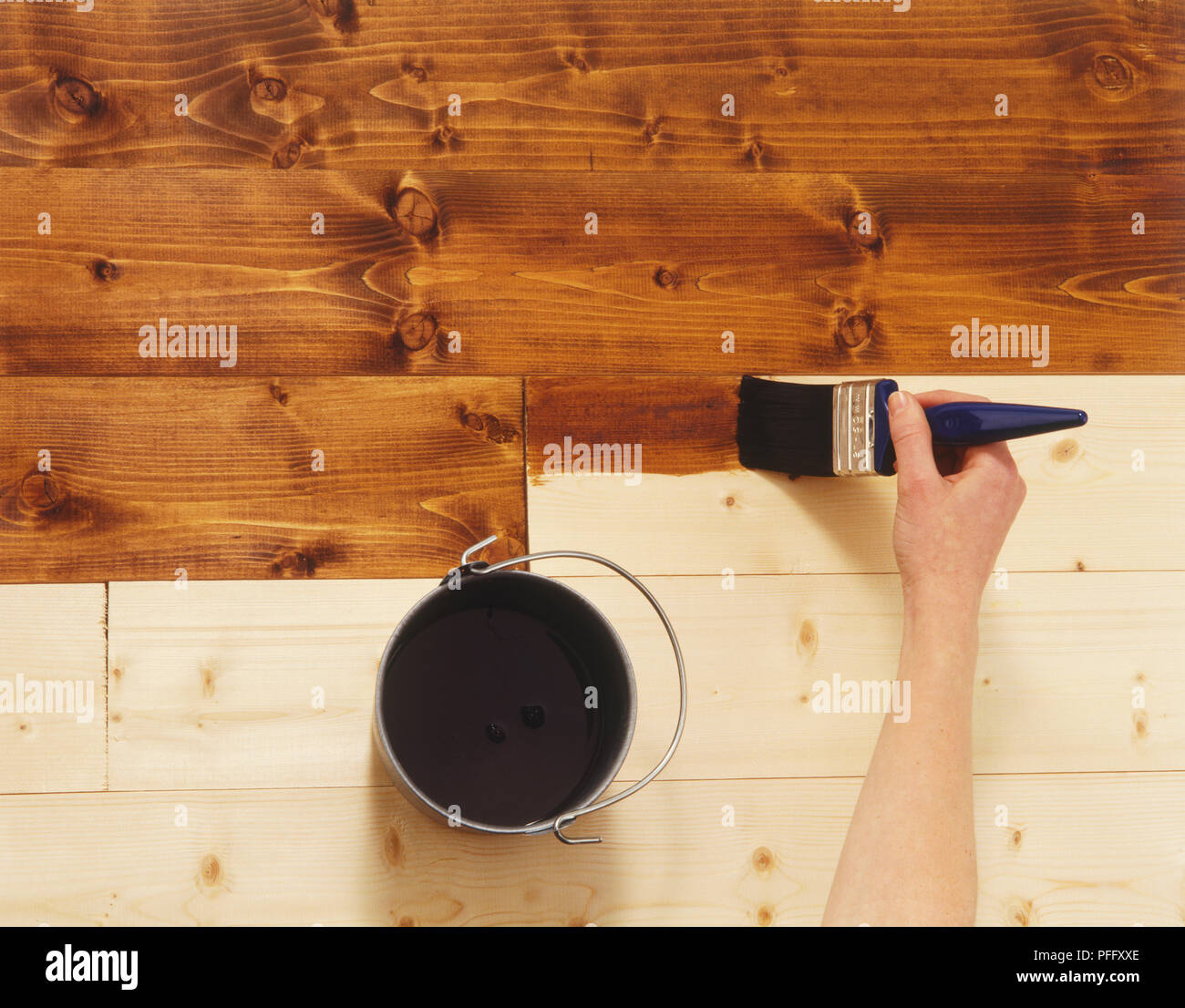 Coloured varnish being applied to floor boards, view from above Stock