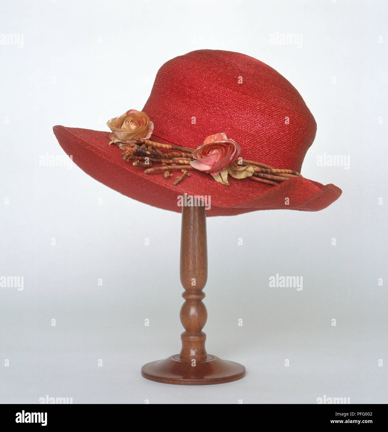 A red straw hat with decorative flowers, on hatstand Stock Photo
