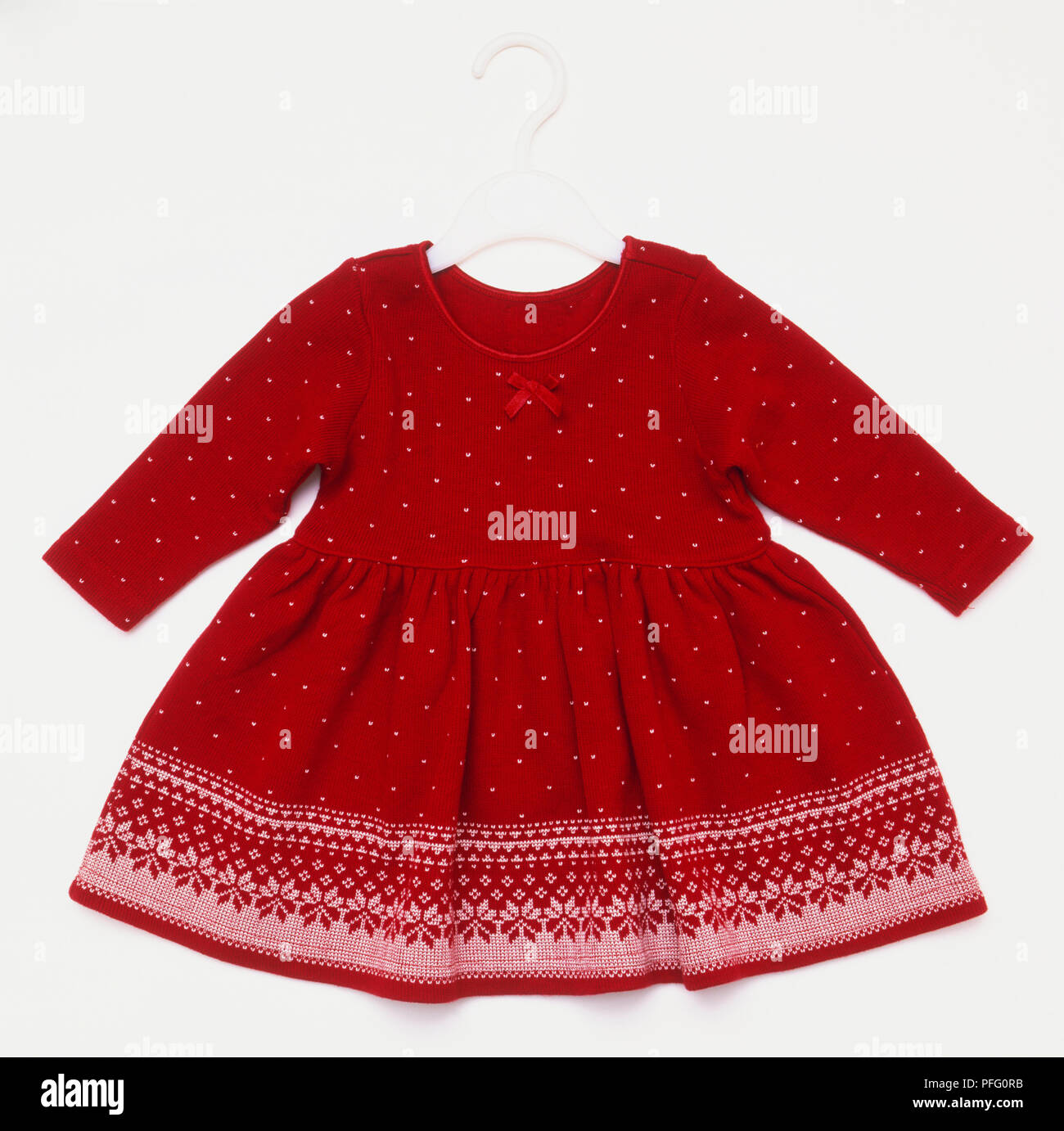Red child's dress with with white polka dots and a wide white border in a snowflake design Stock Photo