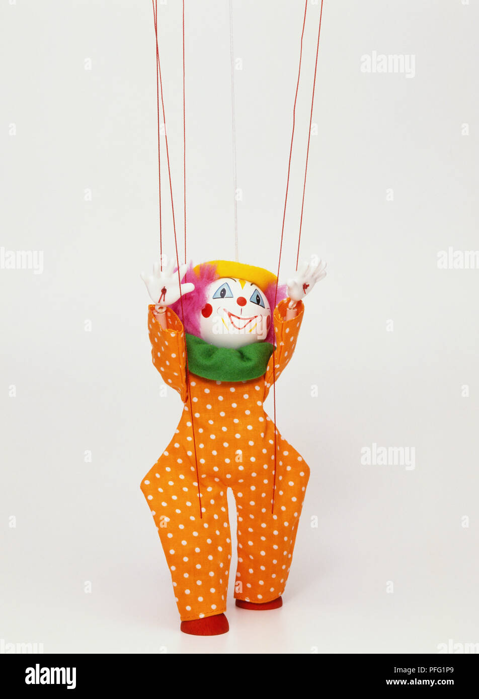 Clown puppet hanging from strings, hands up in air, front view Stock