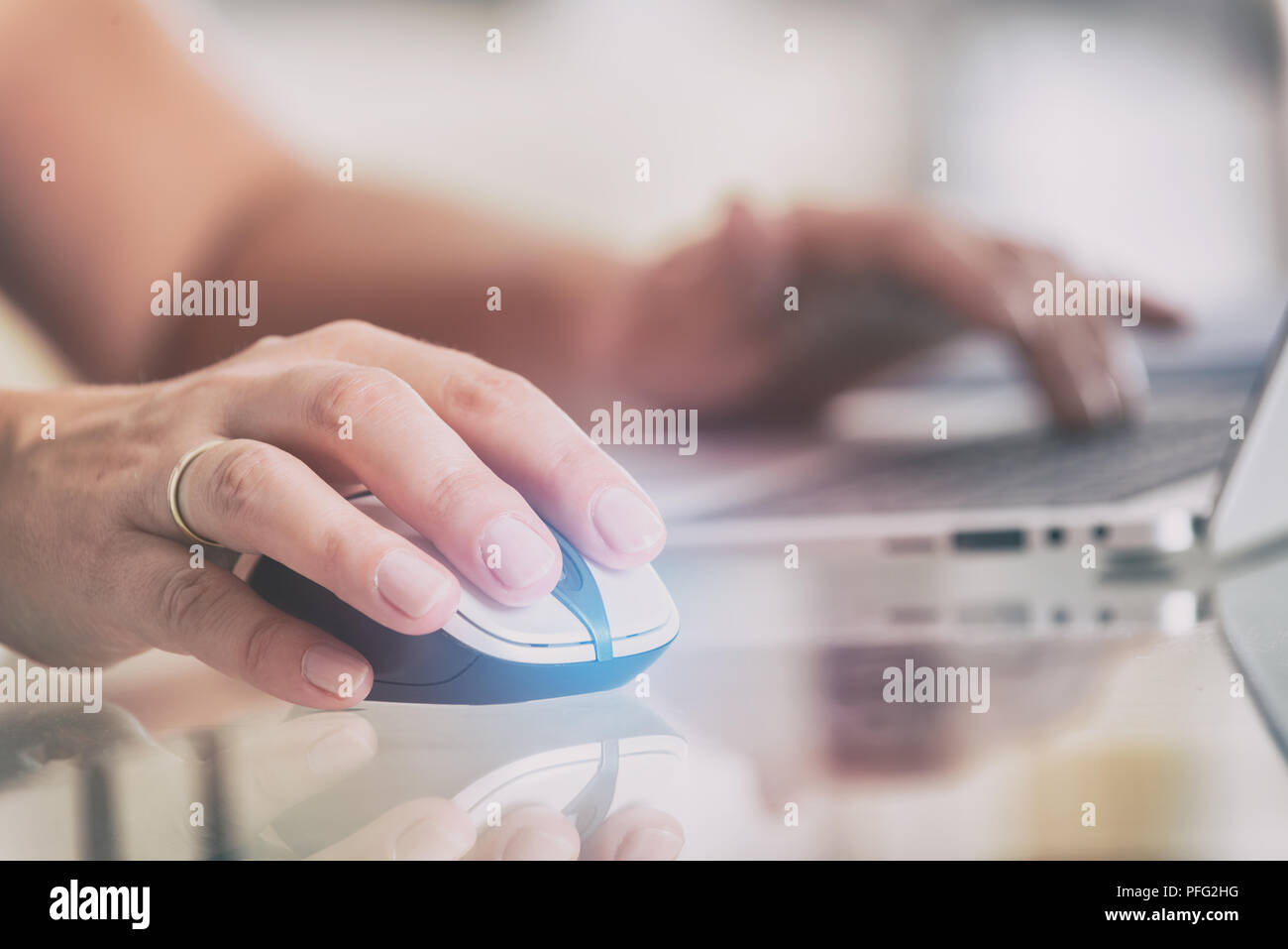 Woman working at home office using laptop, computer mouse in a foreground Stock Photo