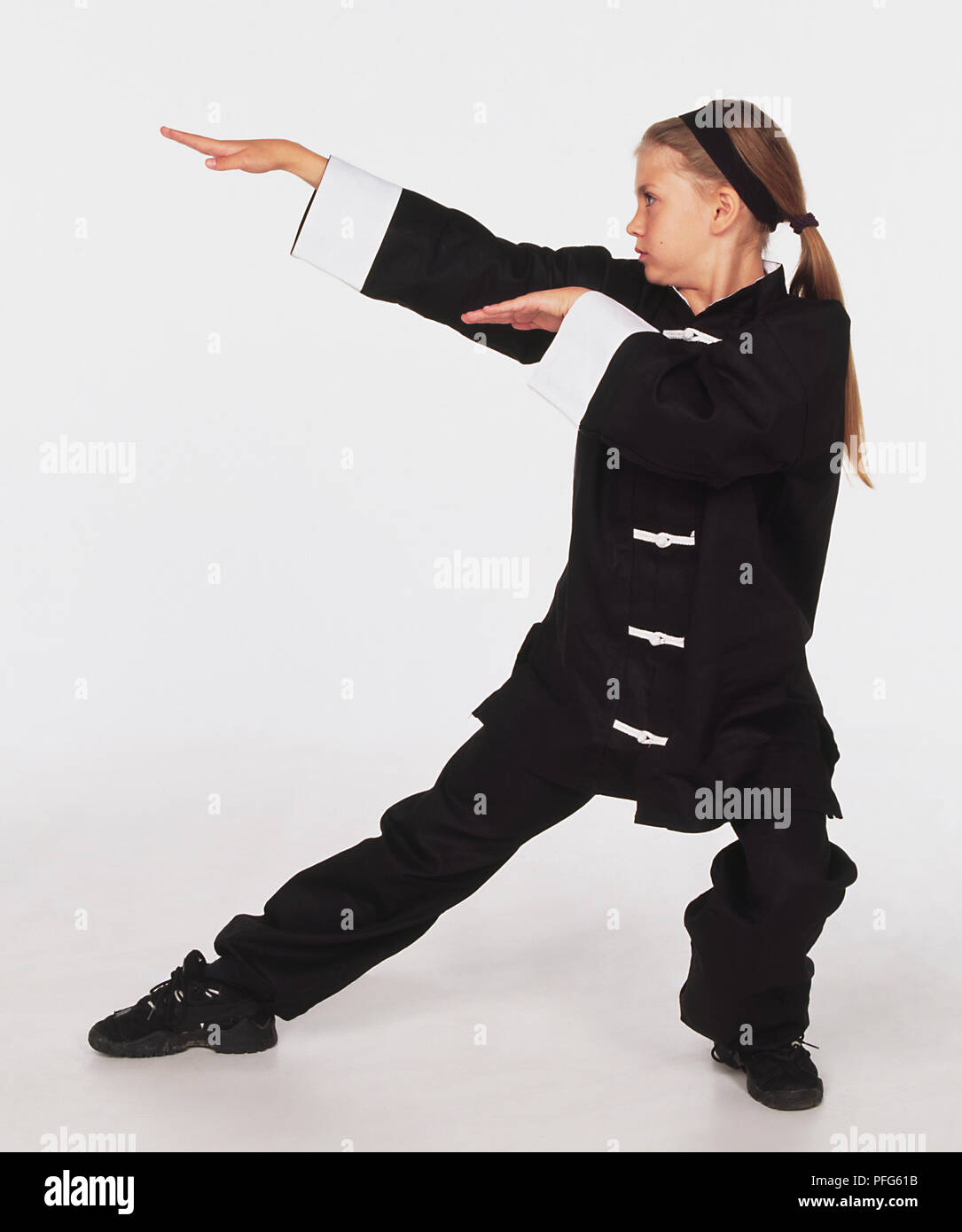 Young girl wearing martial arts uniform performing The snake stance. Stock Photo