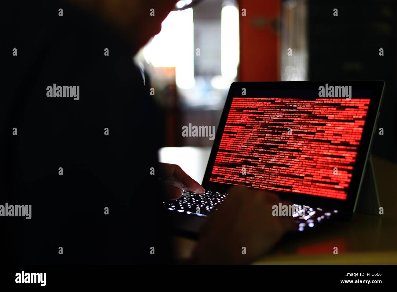 Computer Hacker silhouette typing on computer in a dark room. Working on binary code technology. binary data, computer crime and network security Stock Photo