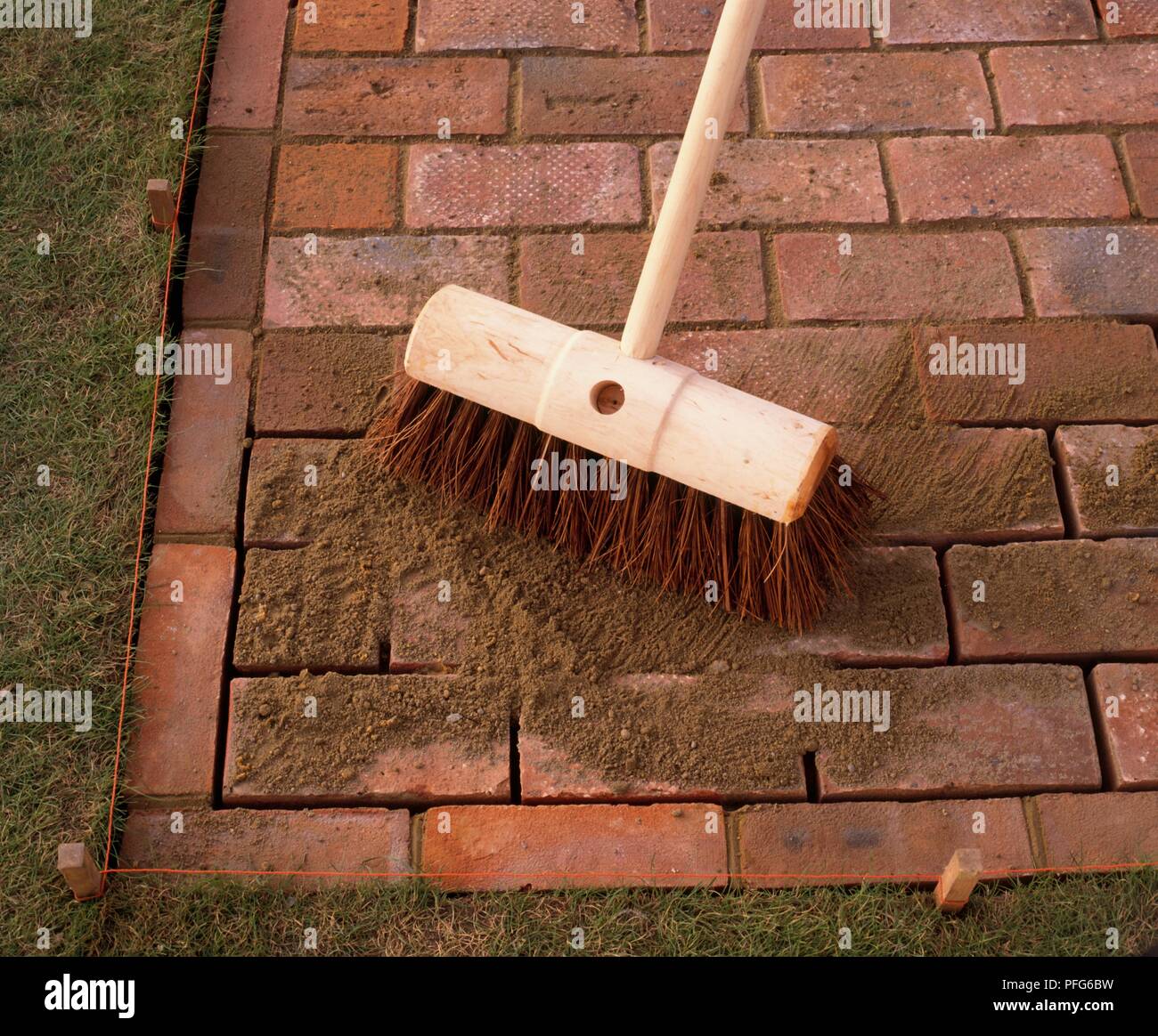 Brushing mortar into gaps between paving slabs, using a broom Stock Photo