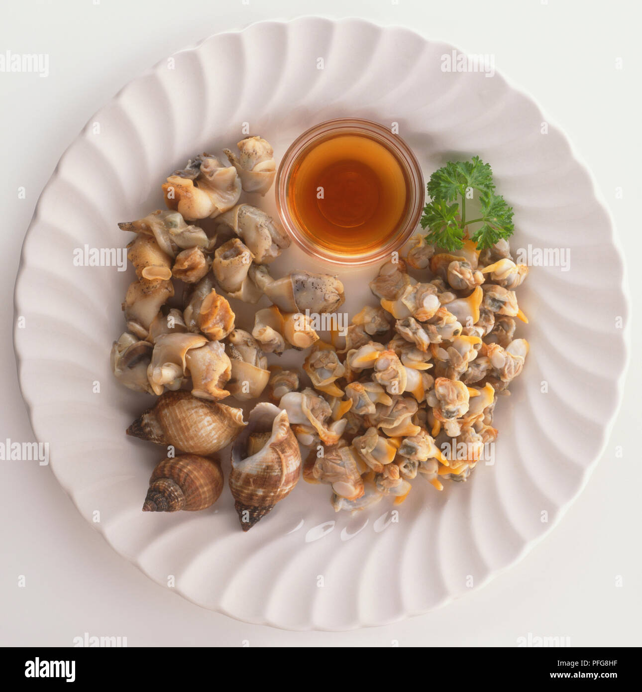 Plate of cockles and whelks, a traditional British dish, served with bowl of vinegar, view from