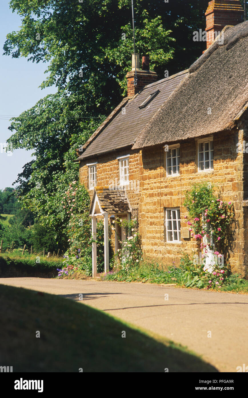 Great Britain, England, Oxfordshire, nr Banbury, thatched cottage on quiet country road, facade, side view. Stock Photo