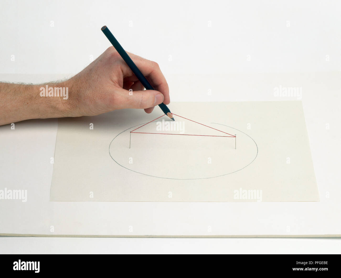 Hand drawing ellipse around a piece of string and two pins Stock Photo