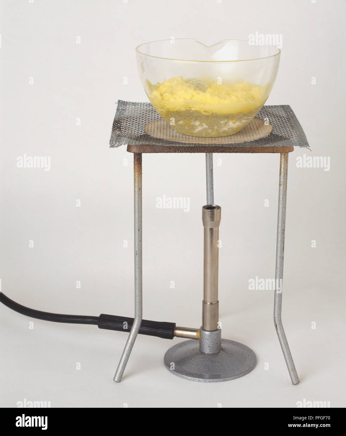 Glass dish with suspension of sulphur in sodium sulphite heated on a tripod. Stock Photo