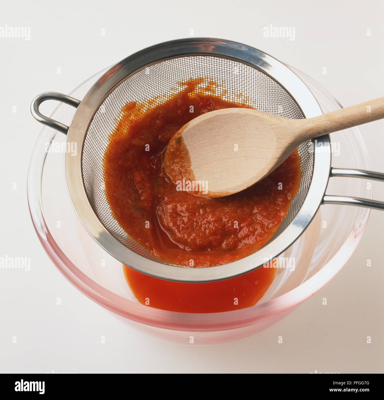 https://c8.alamy.com/comp/PFGG7G/extracting-liquid-from-tomato-pulp-by-passing-it-through-a-mesh-strainer-PFGG7G.jpg