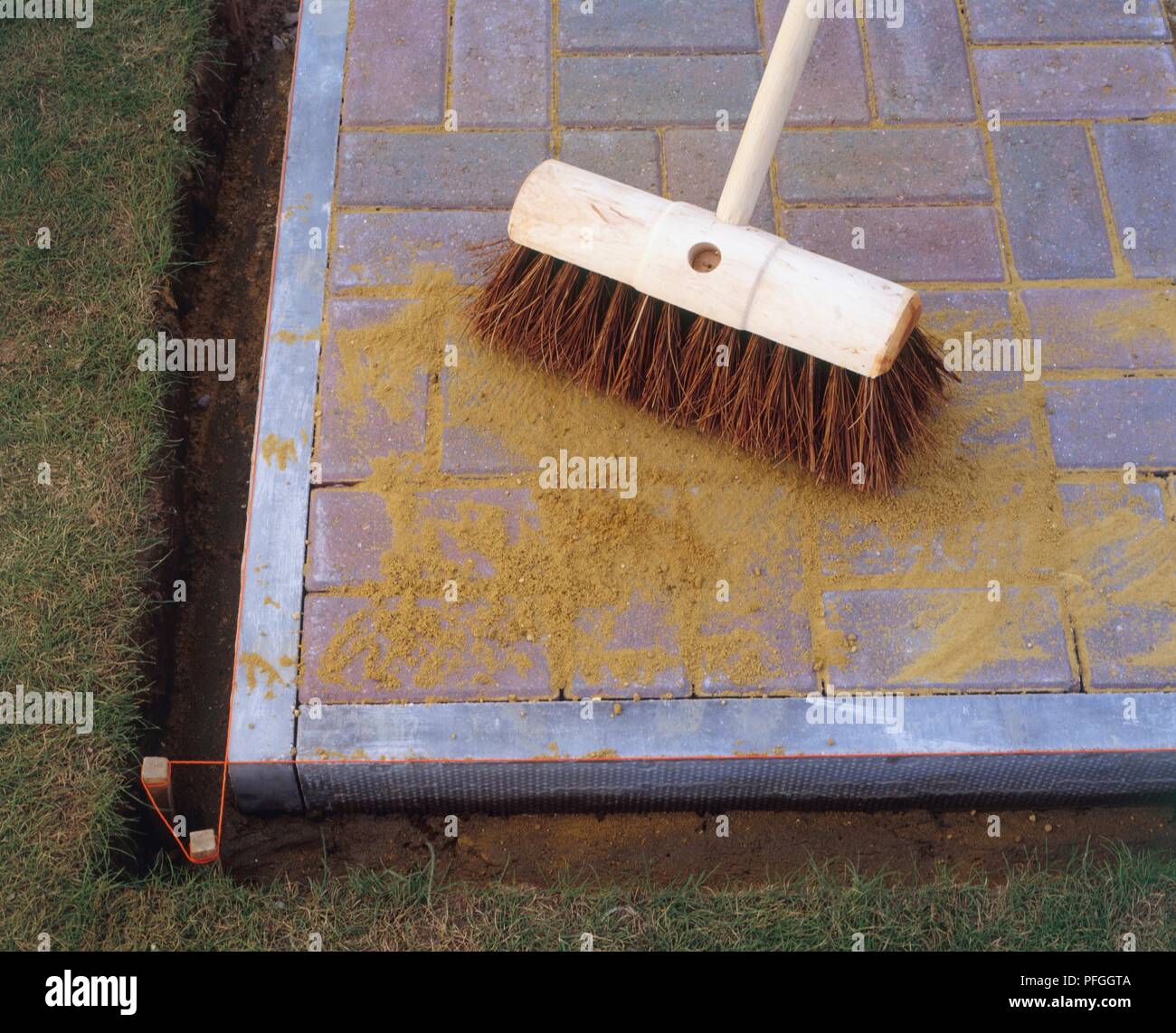 Sweeping sand into gaps between paving stones, closeup Stock Photo Alamy