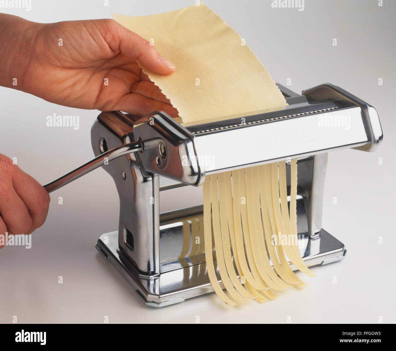 Using pasta machine to cut tagliatelle. Stock Photo