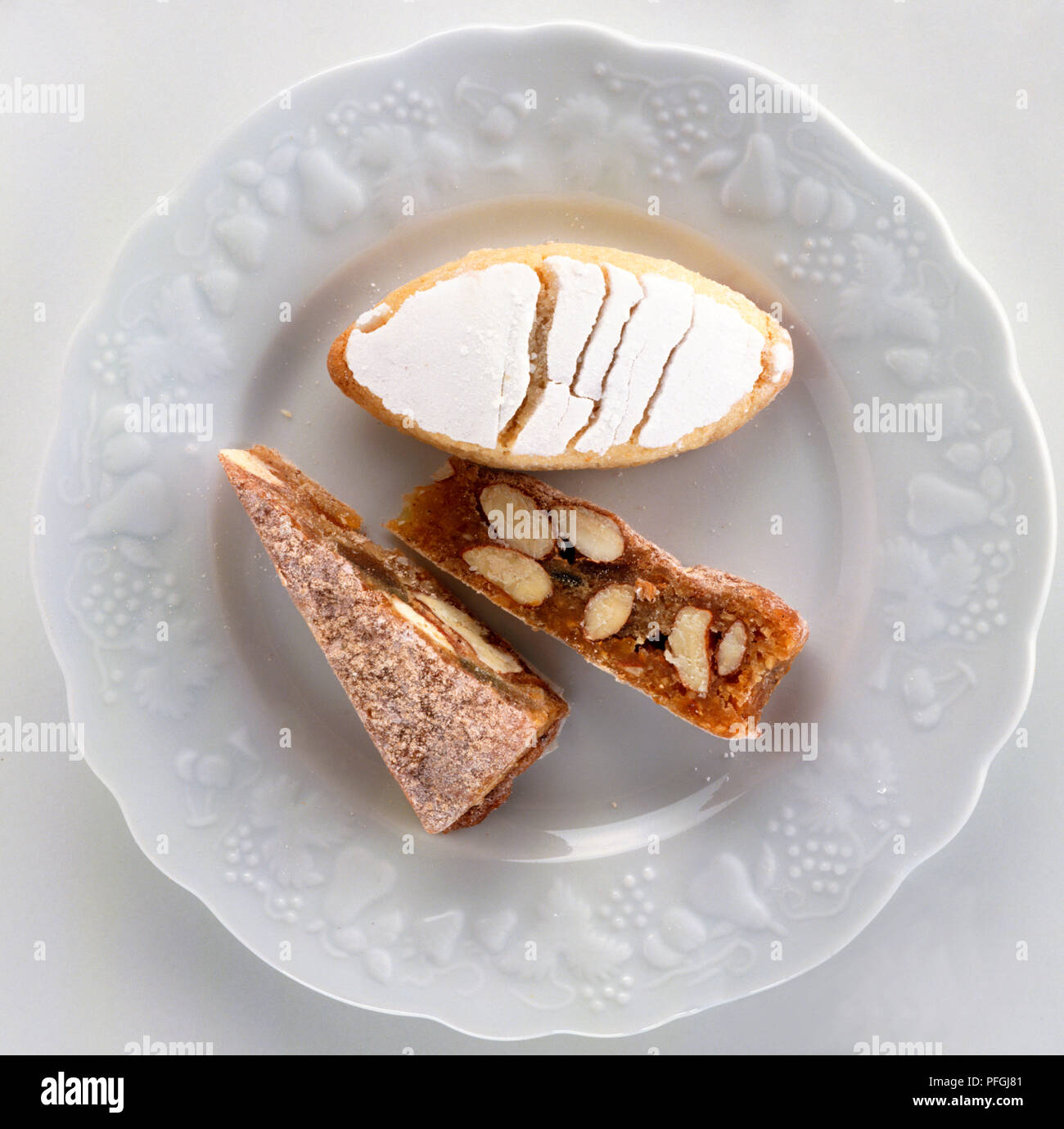 Slices of Panforte, dense dark cake spiced with cloves and cinnamon, and oval-shaped Ricciarelli made from almonds, orange and honey. Stock Photo