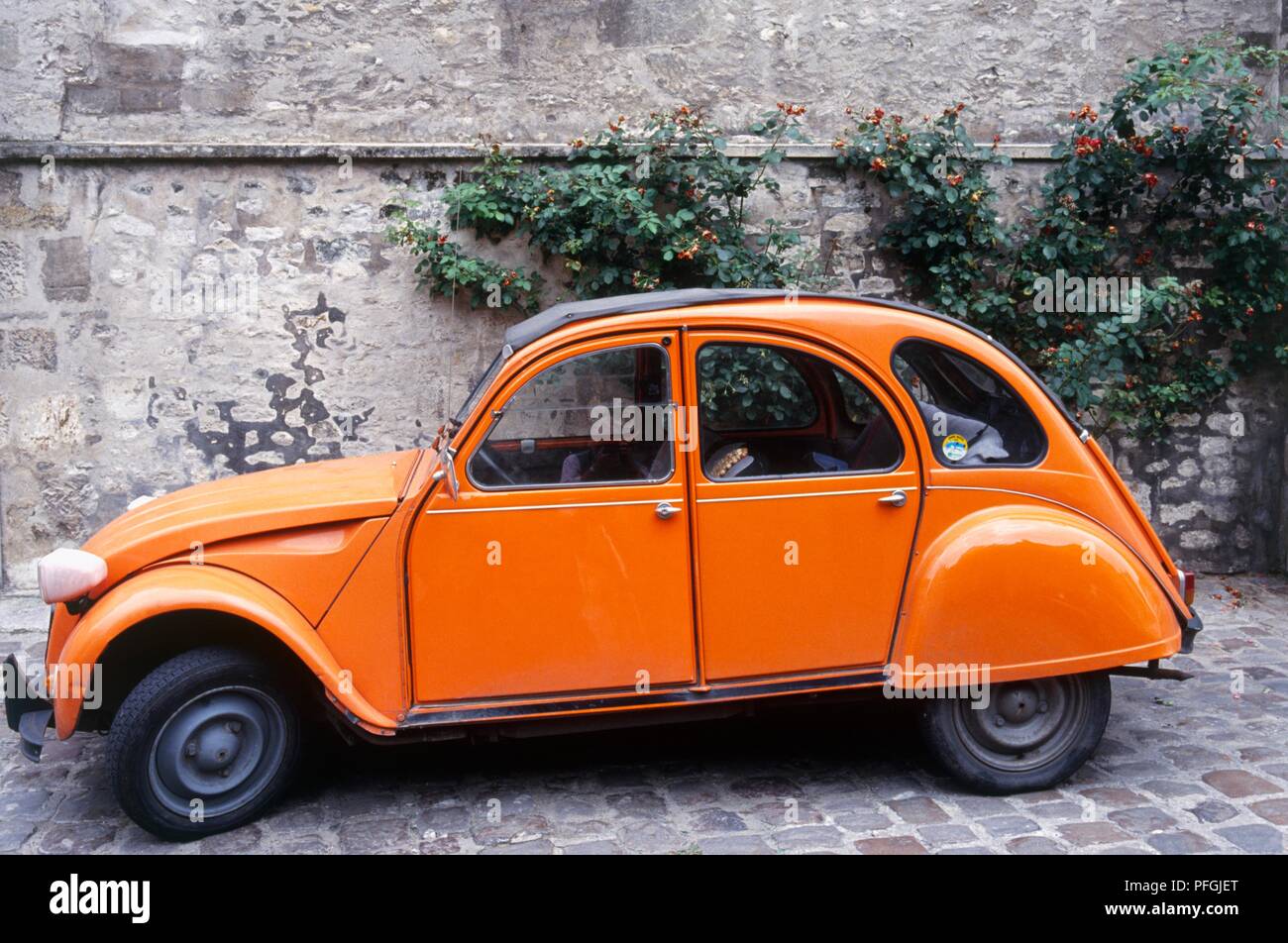 France, an orange Citroen 2CV parked in a cobbled street Stock Photo