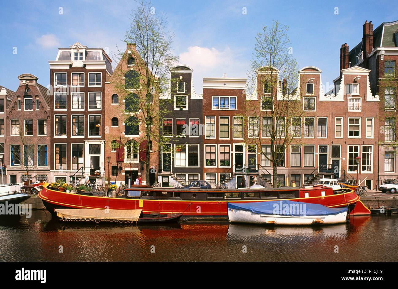 Holland, Amsterdam, house boat on canal with traditional homes in the background. Stock Photo